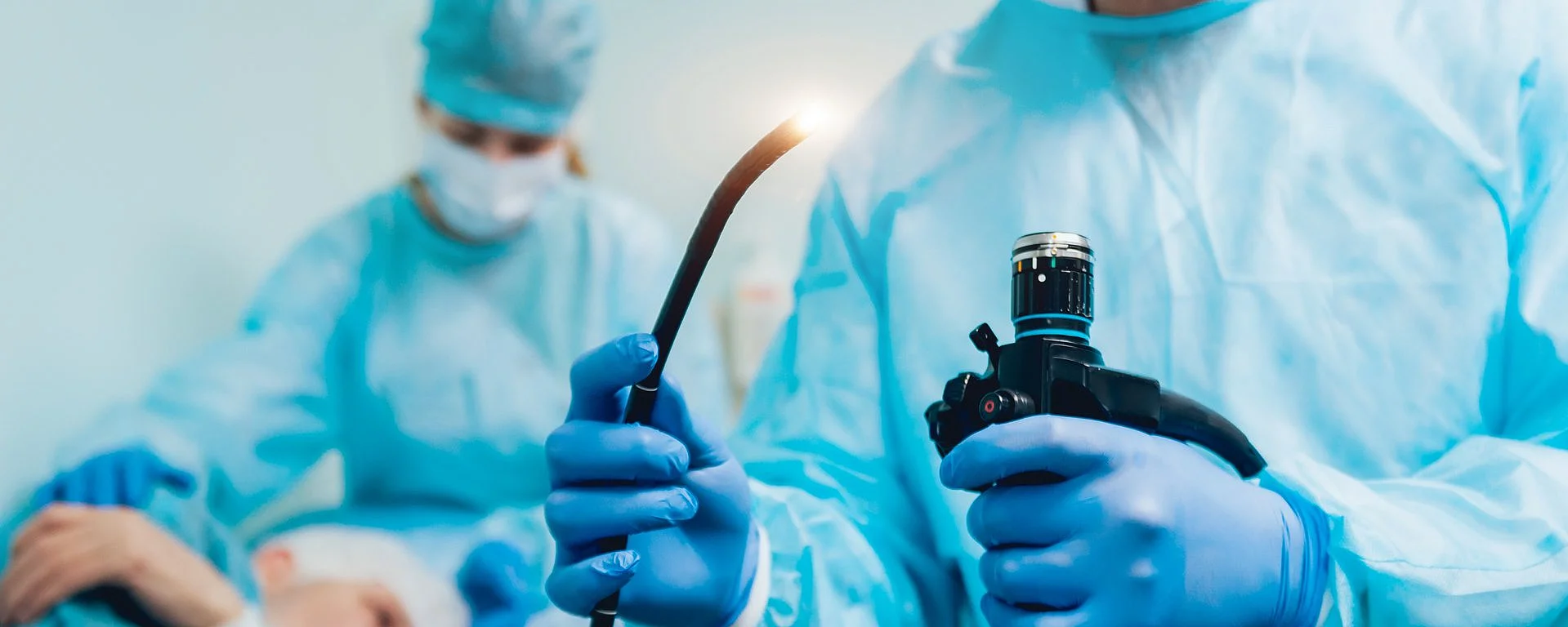 Arzt bereitet eine Endoskopie vor, während ein älterer Patient im Hintergrund für den Eingriff vorbereitet wird – moderne Diagnostik im Pankreaszentrum