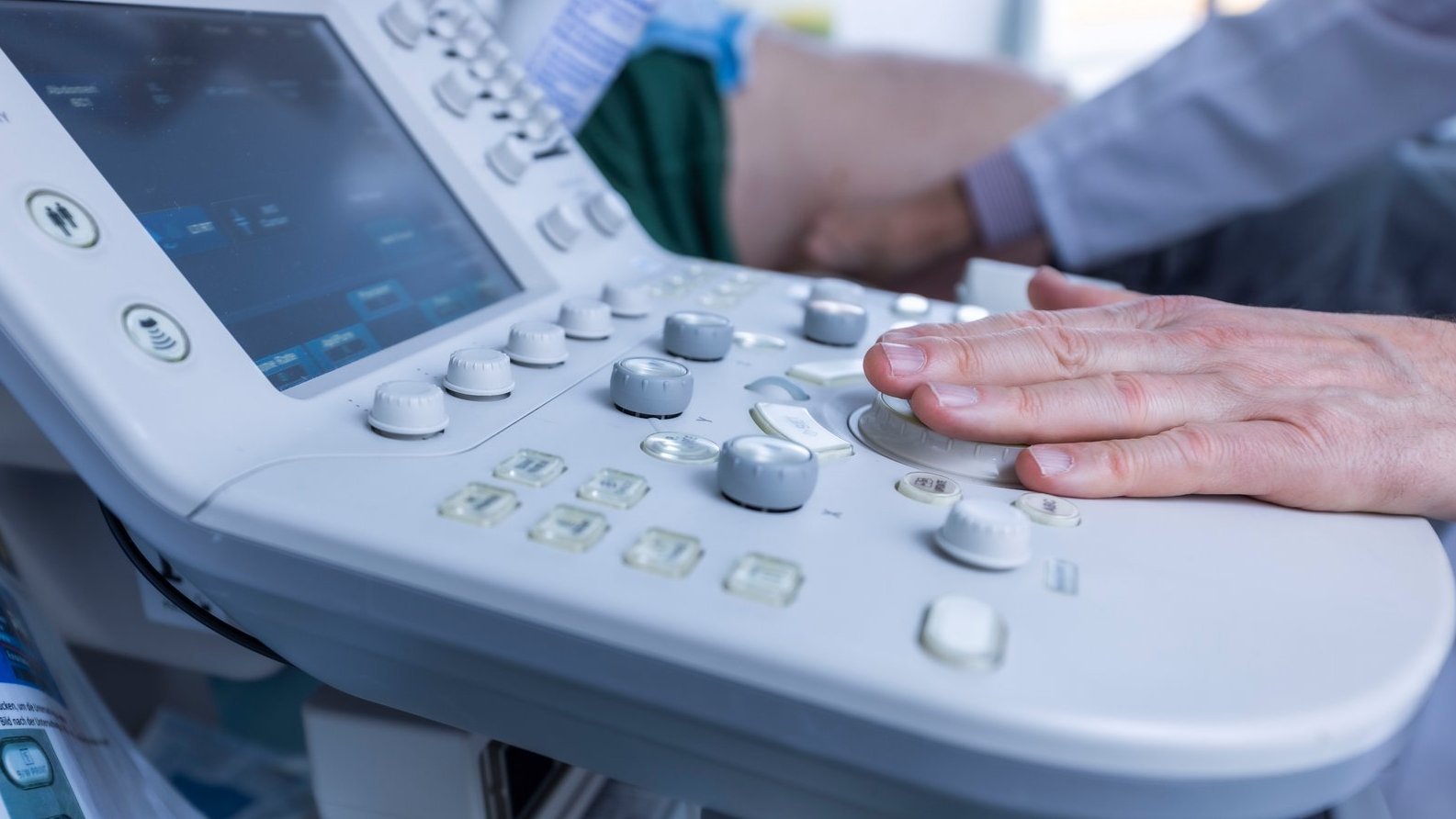 Nahaufnahme eines modernen Ultraschallgeräts, das von einem Arzt im AKH Celle während einer Untersuchung bedient wird.