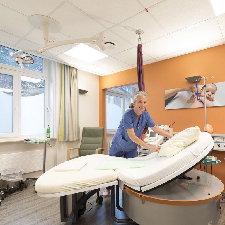 Geburtshelferin richtet das Bett in einem modernen Kreißsaal her.