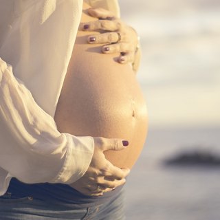 Frau hält ihren schwangeren Bauch.