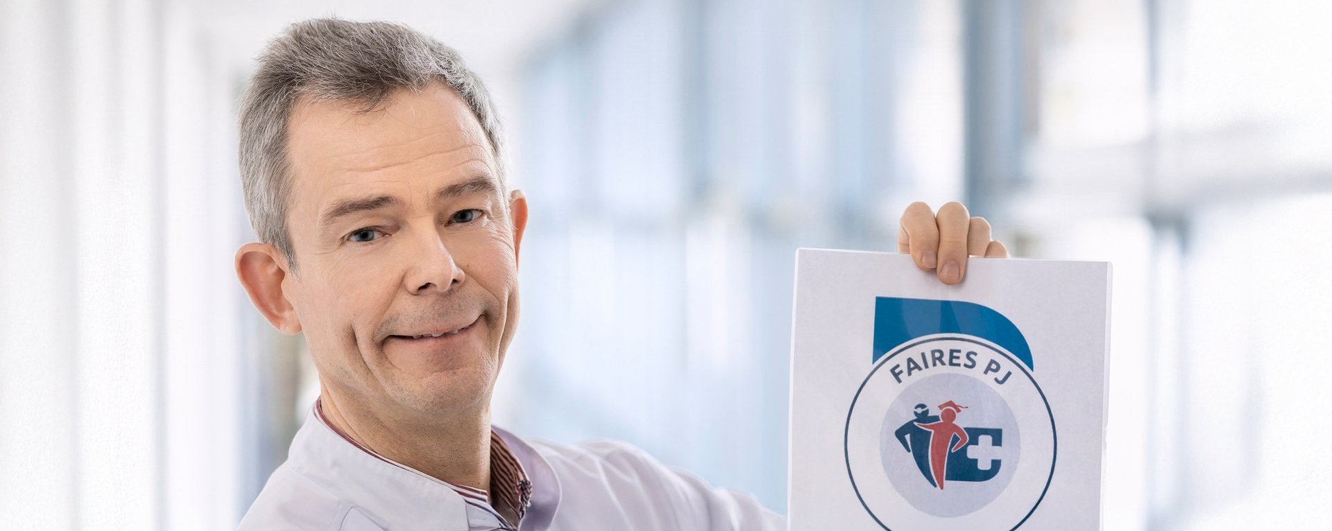 Ein Arzt hält ein ein Zertifikat in der Hand. Auf dem Zertifikat steht „Faires PJ 2023“ und ist von ethimedis.