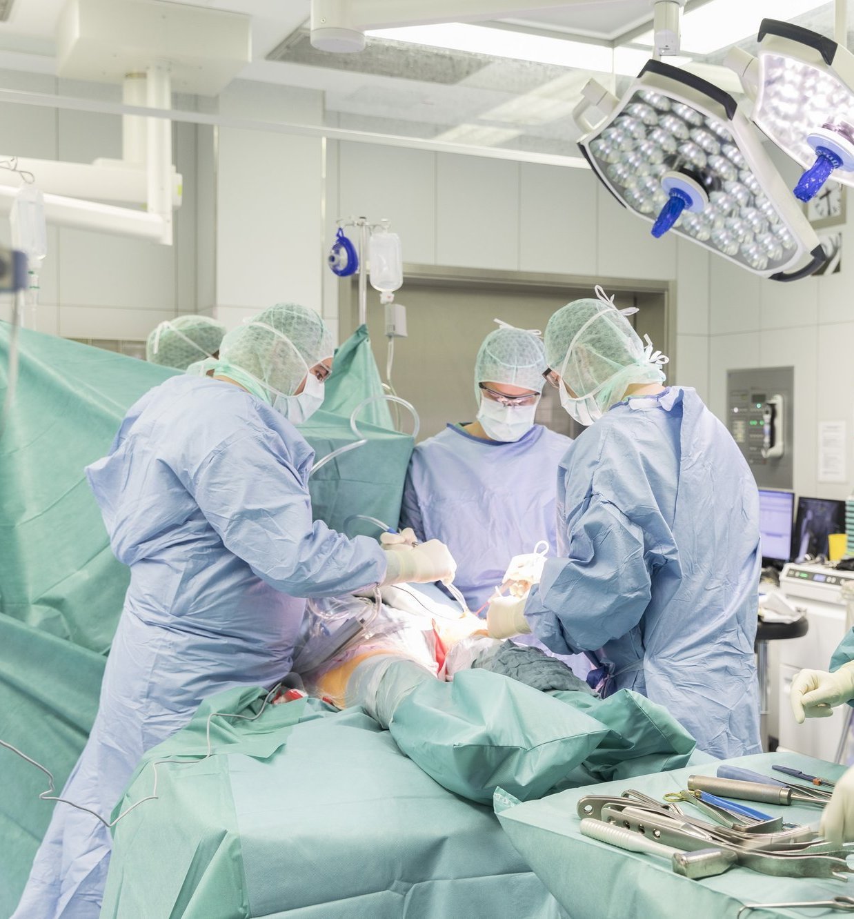 Operationsteam in steriler Kleidung führt Eingriff in einem hochmodernen OP-Saal durch.