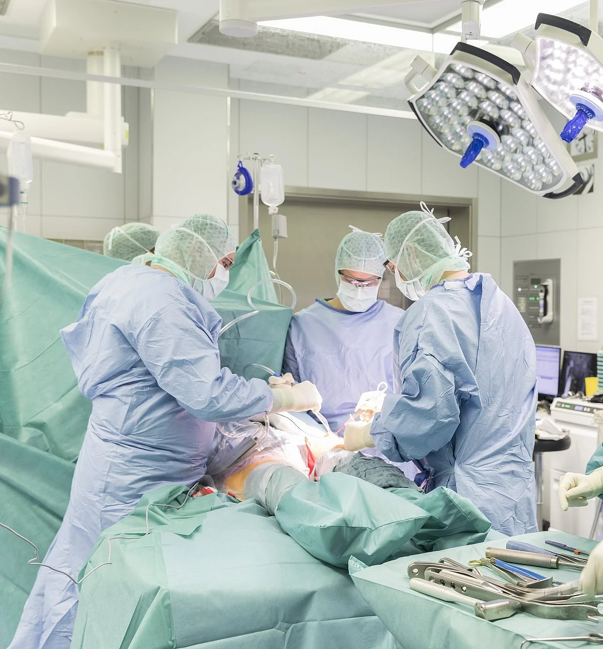 Operationsteam in steriler Kleidung führt Eingriff in einem hochmodernen OP-Saal durch.