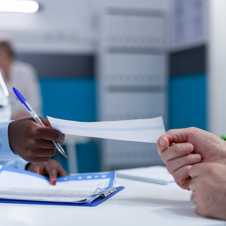 Close up of clinic specialist medic handing over analysis report and consultation result to senior patient. General practitioner giving sick elderly man prescribed medicine for curable ilness Nahaufnahme eines Klinikspezialisten, der einem älteren Patienten den Analysebericht und das Beratungsergebnis überreicht.