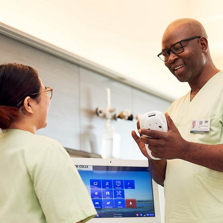 Ein Pfleger erklärt seiner Kollegin etwas anhand eines Tablets in einem Stationszimmer.